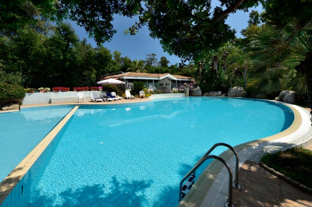 Piscina all'aperto circondata da alberi e sedie a sdraio, atmosfera rilassante.