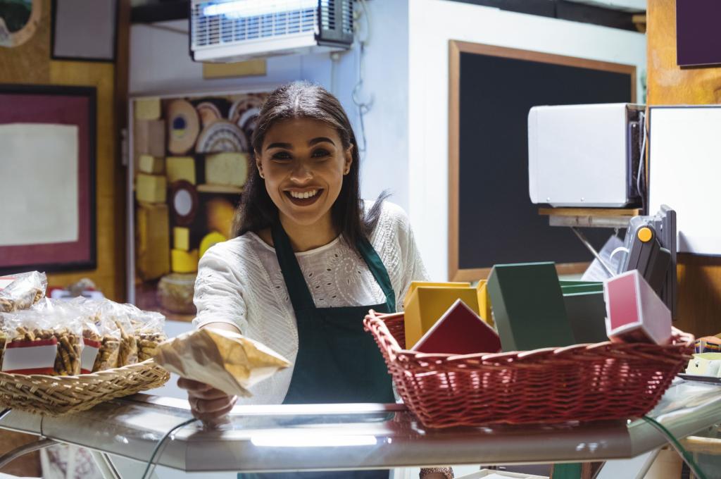 Smiling shopkeeper offers a package in a cozy bakery.