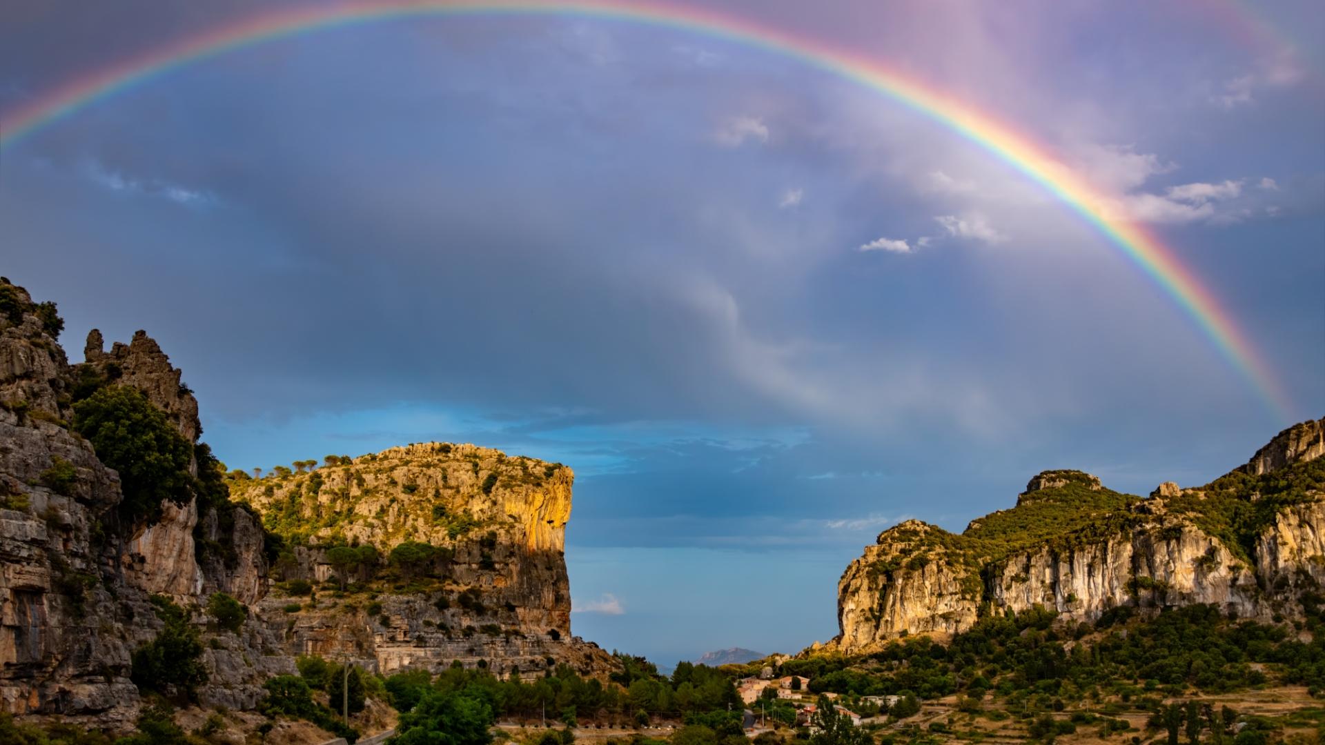 Lebendiger Regenbogen über majestätischen Klippen bei Sonnenuntergang, ruft Ruhe und Staunen hervor.