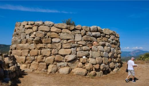 Antica struttura in pietra, tipica dell'architettura nuragica, in un paesaggio rurale.